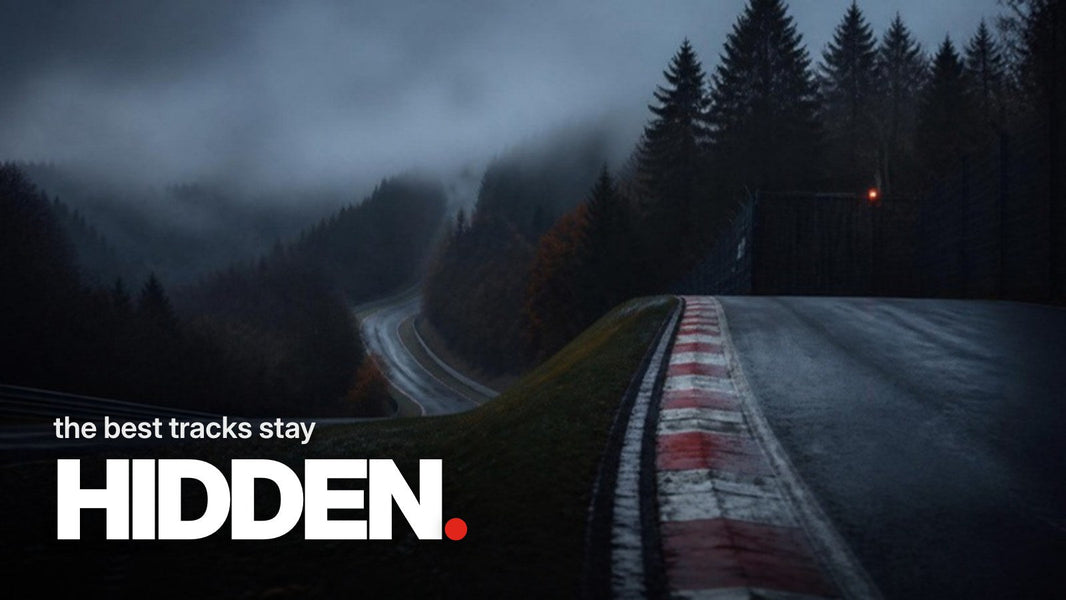Text 'the best tracks stay HIDDEN.' above a dark photo of a remote racetrack with red-and-white curbs, a steep crest, and fog between forested hills at dusk.