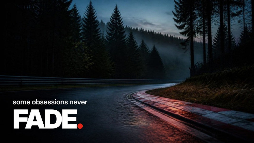 Text 'some obsessions never FADE.' above a photo of a misty forest race track at dusk with wet red-and-white curbs in a turn.