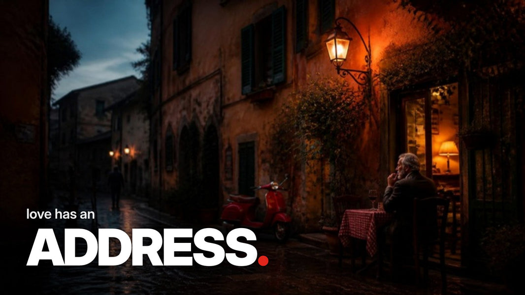 Schriftzug ‚love has an ADDRESS.‘ über einem Foto einer regennassen italienischen Altstadtgasse in der Dämmerung mit warm beleuchtetem Trattoria-Eingang und ockerfarbenen Fassaden.