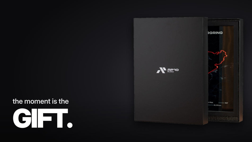 Text 'the moment is the GIFT.' above a close-up of the red 3D section of the Nürburgring Nordschleife with a shadow cast behind a reflective acrylic panel.